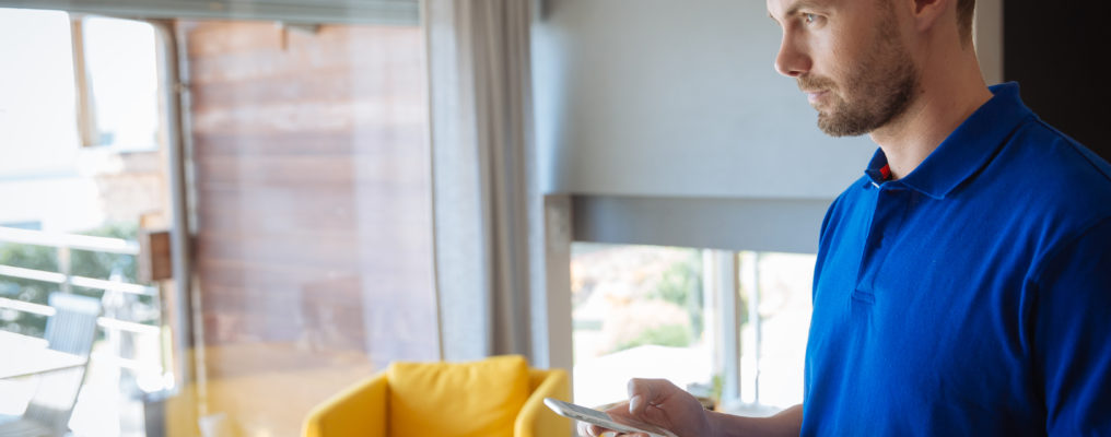 mężczyzna w salonie zarządza domem dzięki aplikacji w telefonie